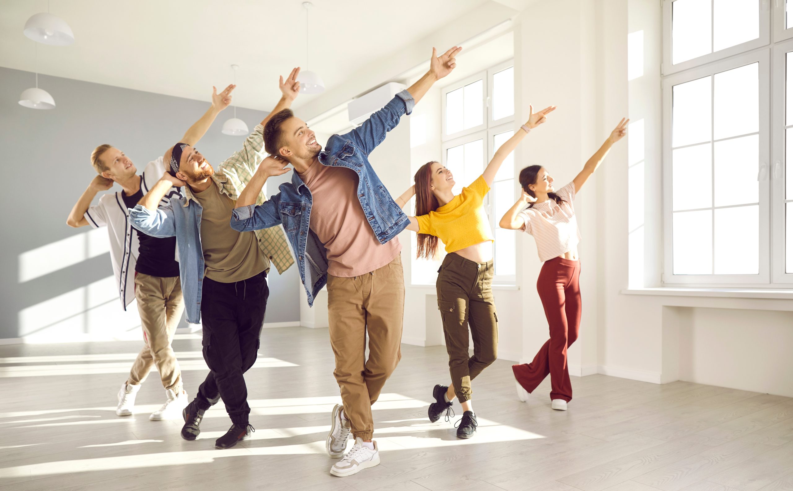 Happy energetic young hip-hop dancers dance together in bright spacious dance studio.