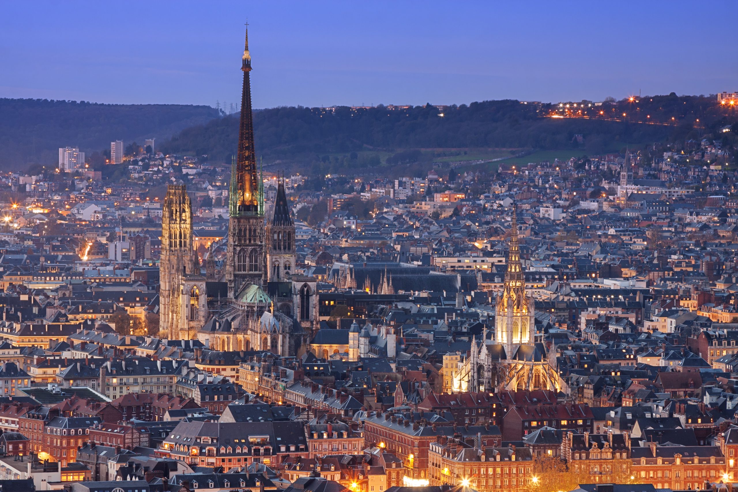 Rouen skyline. Evening cityscape of Rouen featuring the illuminated Rouen Cathedral and surrounding historic buildings at dusk.