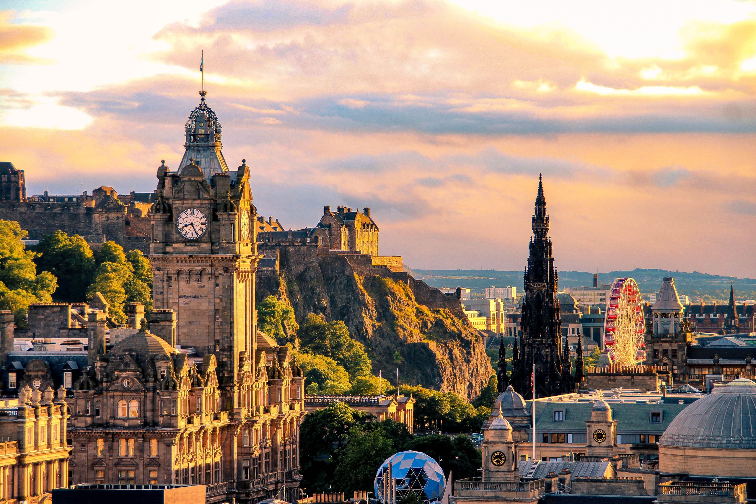 Edinburgh skyline, Scotland Edinburgh city skyline at sunset, showing historic buildings, a clock tower, and the Scott Monument with Edinburgh Castle in the background.
